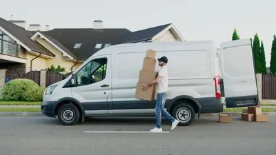 Persona cargando cajas hacia una camioneta de mudanza